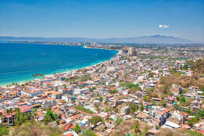 High angle view of townscape by sea against blue sky