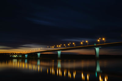 Illuminated bridge over river against sky at night