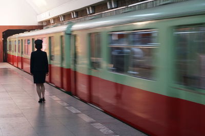 Blurred motion of train by woman standing at platform