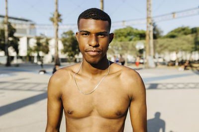 Shirtless man at basketball court during sunny day