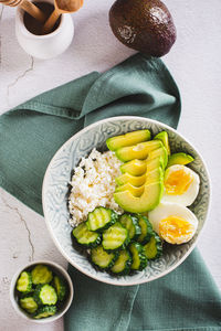 Fresh cottage cheese, avocado, cucumber and boiled egg in a plate top and vertical view