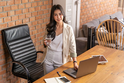 Portrait of smiling young man using laptop at table