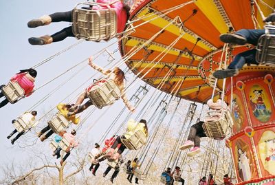 Low angle view of people enjoying on chain swing ride