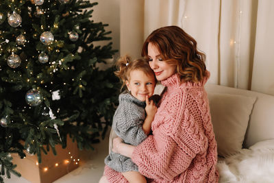 Happy mom and daughter child celebrate the christmas holiday in the decorated room of the house