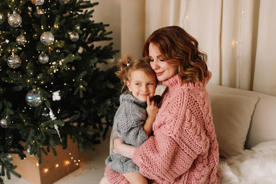 Portrait of girl playing with christmas tree at home