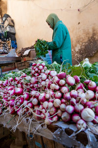 Rear view of woman holding vegetables for sale at market stall