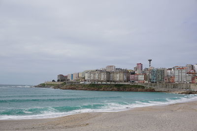 Sea by buildings against sky in city