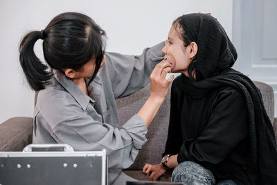 Side view of young woman using laptop at home