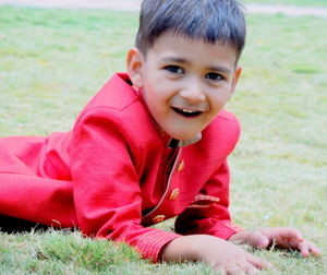 Portrait of boy in red traditional clothing lying down on field