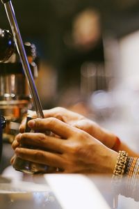 Cropped hands making coffee from espresso maker in cafe