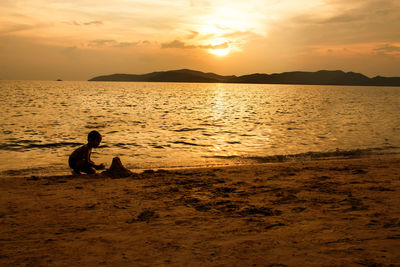 Silhouette people on beach against sky during sunset