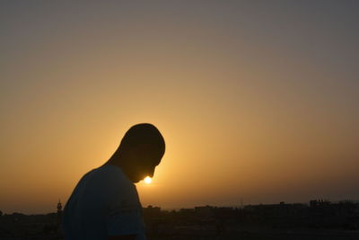 Silhouette man photographing against sunset sky