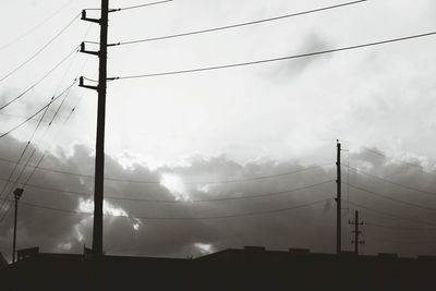 Low angle view of silhouette electricity pylon against sky