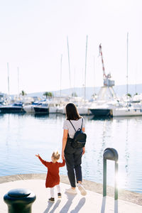 Rear view of people on sailboat at harbor against sky