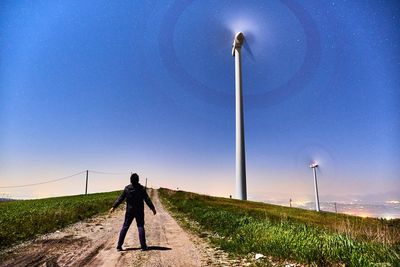 Rear view of man walking on street light against blue sky