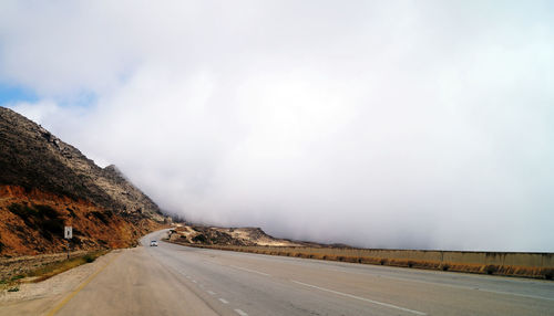 Road by mountain against sky