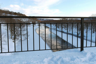 Fence by trees against sky during winter