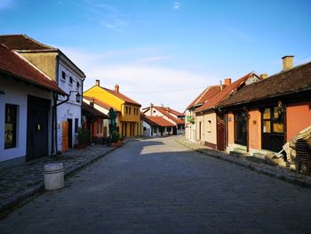 Footpath amidst houses and buildings against sky