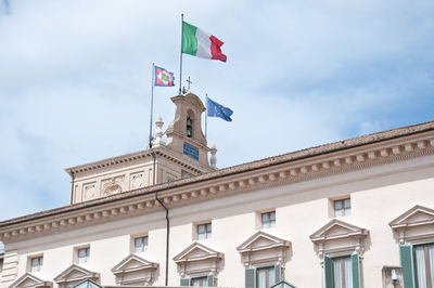 Low angle view of flags on building against sky