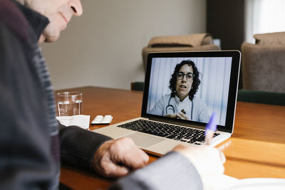 Midsection of man using mobile phone while sitting on table