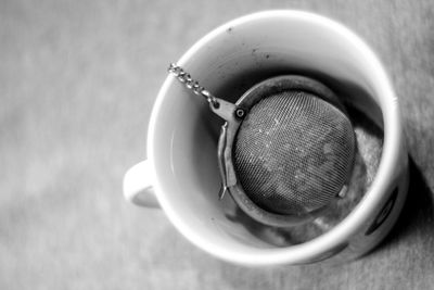 High angle view of tea strainer in cup on table