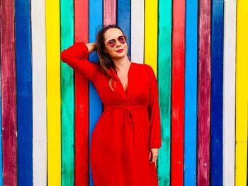 Portrait of woman in dress standing against multi colored wall