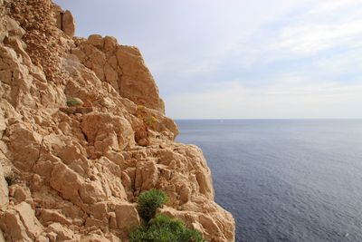 Rock formations by sea against sky