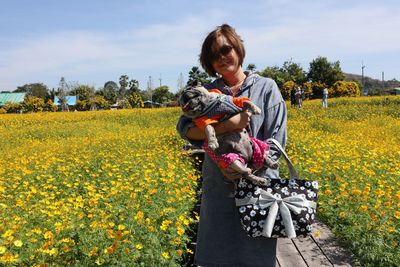 Woman standing on field against yellow flowers