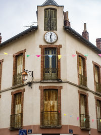 Low angle view of clock tower against building in city