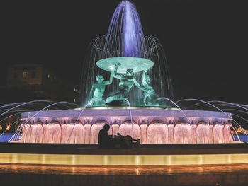 Statue in illuminated city against sky at night