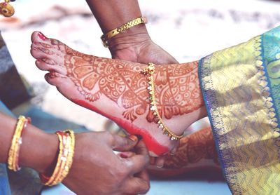 Cropped image of woman applying alta dye on bride foot