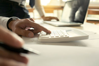 Close-up of man using laptop on table