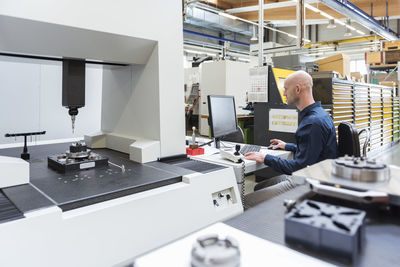 Man using computer at machine in modern factory