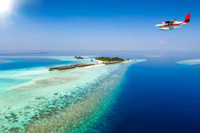 Seaplane flying over sea against sky