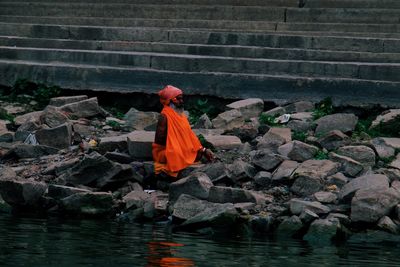 Rear view of man sitting on rock