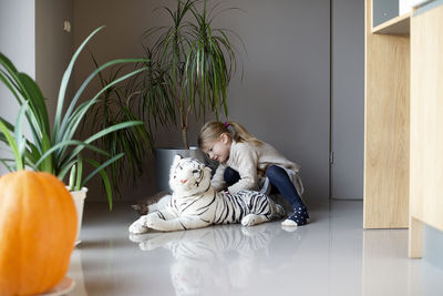 A little girl sits on the floor and holds a cat in her hands