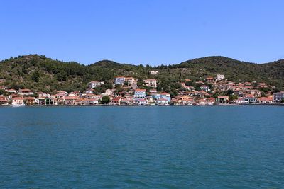 Townscape by sea against clear blue sky