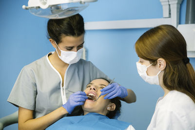 Dentists examining pregnant woman in clinic