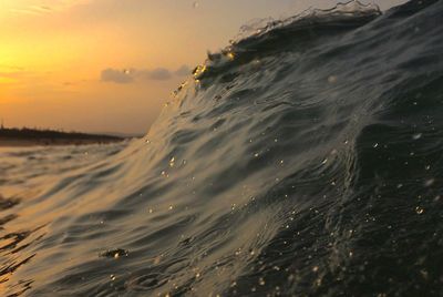 Close-up of sea wave against sky during sunset