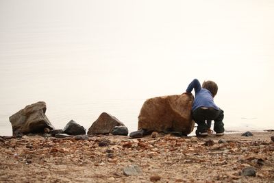 Rear view of men standing on rock against sky