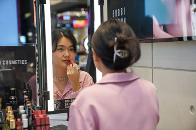 Woman with reflection of people on mirror at home