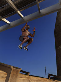 Low angle view of man jumping against clear sky