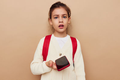 Portrait of young woman using mobile phone against pink background