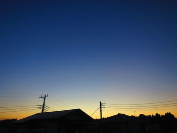 Low angle view of silhouette buildings against blue sky