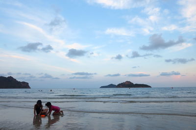 People at beach against sky