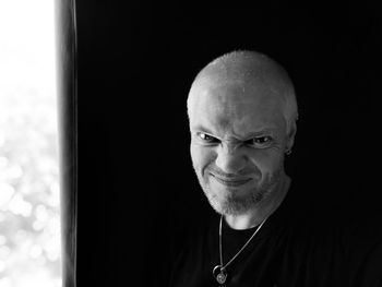 Close-up portrait of smiling man against black background