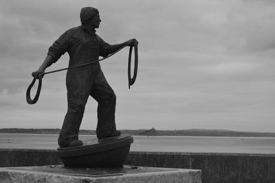 Man standing on boat in sea against sky