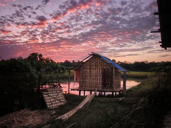 House amidst trees and buildings against sky during sunset