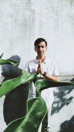 Portrait of young man standing against wall