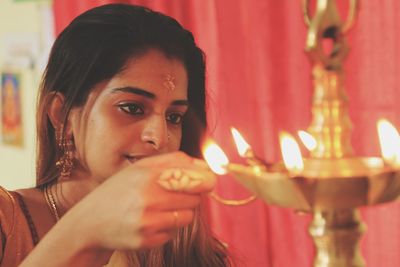 Young woman lighting diya at home